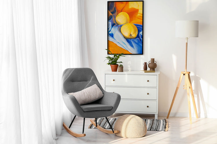 White wooden chest of drawers with grey accent chair and wall art in background