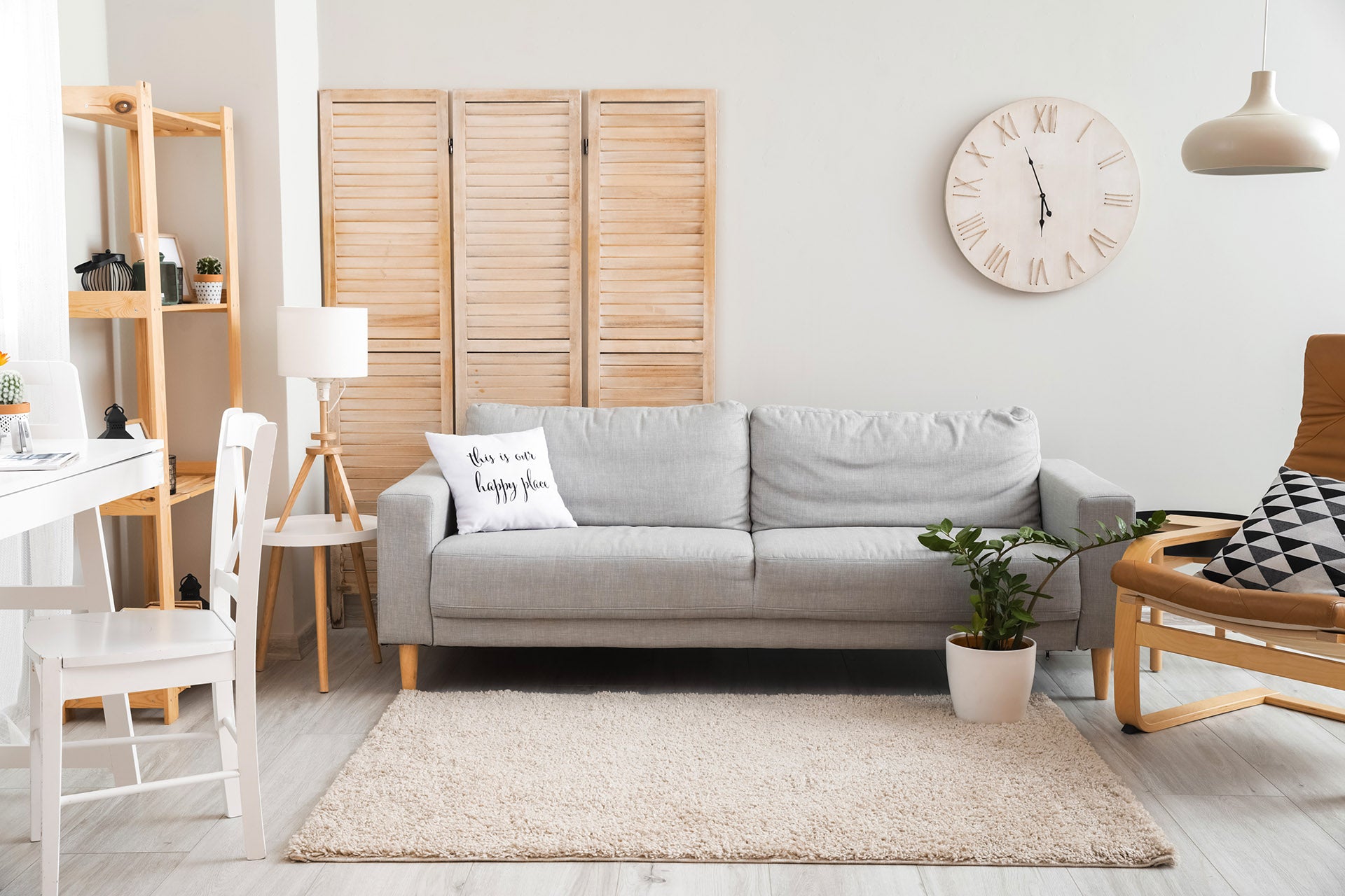 Grey two person sofa bed in modern living room with chairs, table and wall clock