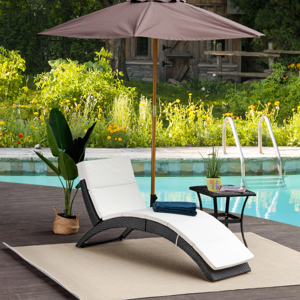 Premium Rattan Sun Lounger with large ergonomic cushion beside pool under a brown patio umbrella