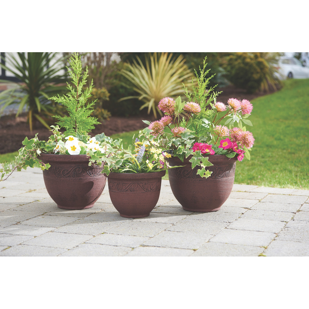 Three brown Eco Friendly Planters (H23x30cm) with mixed flowers on a stone patio.
