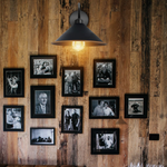 Black Gold Wall Light Medium Swan Neck Cone Shade E27 Home hangs on a wooden wall with black-framed photos, warm glow.